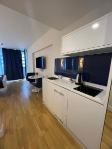 a kitchen with white cabinets and a living room at Orbi city Aparthotel in Batumi