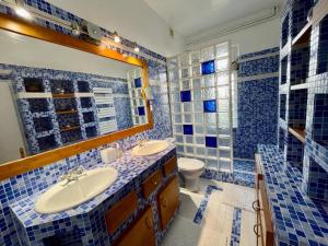 La salle de bains est pourvue de carrelage bleu, d'un lavabo et de toilettes. dans l'établissement Maison cosy, cheminée jardin proche centre ville, à La Gollotte