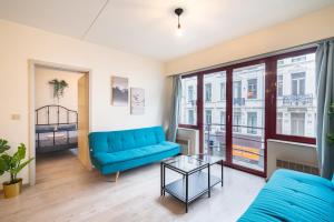 uma sala de estar com um sofá azul e uma mesa de vidro em Bright Apartments In The Heart Of Antwerp em Antuérpia