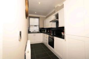 a kitchen with white cabinets and black counter tops at Stones Throw in Scarborough