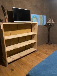 una estantería de madera con un televisor. en CABAÑA en Eco Posada Tierra Fértil, en Santa Ana