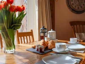 a table with a vase of red tulips and croissants and cups at Sea Haven in Seaton
