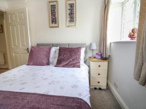 a bedroom with a bed with purple pillows and a window at Sea Haven in Seaton