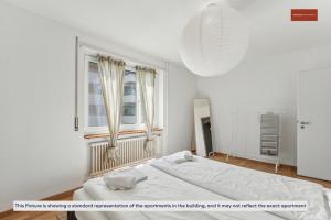 a white bedroom with a bed and a window at 15-Min to Zurich Center: Cozy Apartment in Zurich