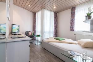 a bedroom with a bed and a desk with a computer at Hotel Cronberger Hof in Ladenburg