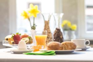 a table with breakfast foods and a glass of orange juice at Hotel Cronberger Hof in Ladenburg