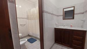 een badkamer met een toilet, een wastafel en een spiegel bij Casa familiar con parrilla y patio compartido in Tandil +5 foto's