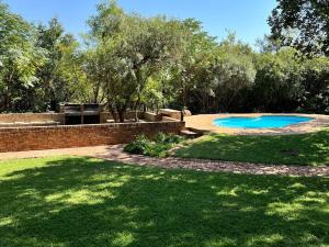 Rayton的住宿－Featherwood Farm & Nyala Lodge，后院设有游泳池,种植了树木和草地