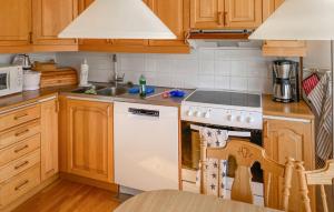 雪平斯维克5 Bedroom Stunning Home In Köpingsvik的厨房配有木制橱柜和白色炉灶烤箱。