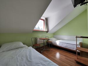 a room with two beds and a table and a window at Pokoje Gościnne Sonia in Tuszyn