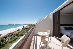 a balcony with a bedroom and a bed and a beach at Wish Natal in Natal