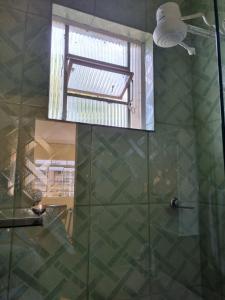 a shower with a glass door and a window at Seu Cantin em BH Venda Nova in Belo Horizonte