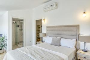 um quarto branco com uma cama e uma cabina de duche ao nível do chão em Can Muntaner Duplex em Palamós
