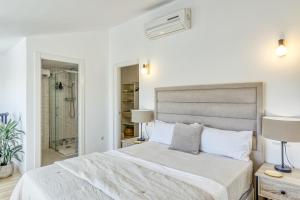 Habitación blanca con cama y ducha a ras de suelo en Can Muntaner Duplex, en Palamós