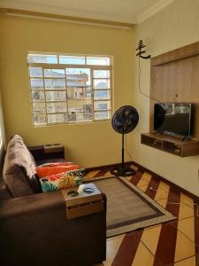 a living room with a couch and a television at Seu Cantin em BH Venda Nova in Belo Horizonte