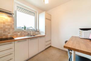 a kitchen with white cabinets and a window at Pokoje Gościnne Dominika in Jastarnia