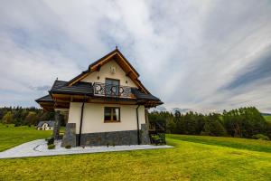 a small house with a balcony on a green field at Domek Bajkowy Widok in Maniowy