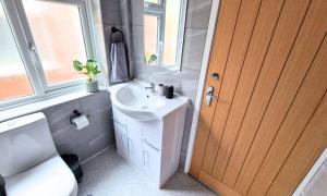 een badkamer met een wastafel, een toilet en een deur bij Luxury Family Apartment- Close to Leicester University in Leicester