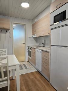 a kitchen with wooden cabinets and a white refrigerator at Levilehto Apartments in Levi