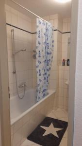 baño con bañera, ducha y alfombra de estrella en Fewo 6, en Gotha