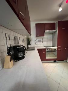 cocina con armarios rojos y suelo de baldosa blanca en Fewo 6, en Gotha