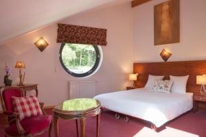 a bedroom with a bed and a round window at La Fischhutte, The Originals Relais (Relais du Silence) in Mollkirch
