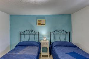 2 Betten in einem Schlafzimmer mit blauen Wänden in der Unterkunft Casa Gianna in Marina di Pescoluse