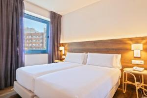 a hotel room with a large white bed and a window at Hotel Acta Azul Barcelona in Barcelona
