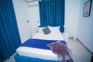 a bedroom with a large bed with blue curtains at The Pearl - Bountiful - 1st floor in Kumasi