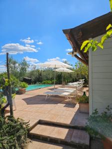 um pátio com um guarda-sol e uma piscina em La Masseria Casa Vacanze em Empoli