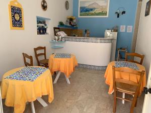2 tables et des chaises dans une pièce aux murs bleus dans l'établissement Bed & Breakfast Sole Azzurro, à Custonaci