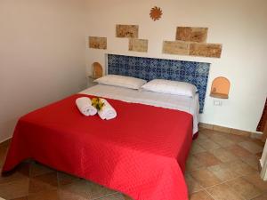 a bedroom with a red bed with towels on it at Bed & Breakfast Sole Azzurro in Custonaci