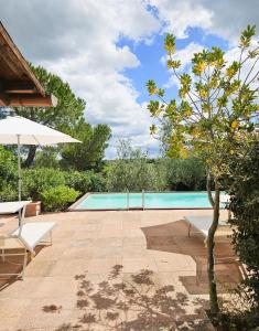 a swimming pool with two chairs and an umbrella at La Masseria Casa Vacanze in Empoli