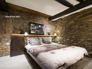 1 dormitorio con 1 cama en una pared de piedra en Gîtes de la Maison Vigneronne, au Coeur de Ribeauvillé, en Ribeauvillé