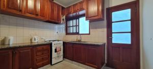 een keuken met houten kasten en een witte kookplaat bij Casa familiar con patio y parrilla in Tandil