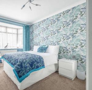 a bedroom with a bed with a blue and green wallpaper at Large Bungalow to sleep up to 8 in Slough