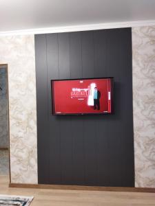 - une télévision à écran plat sur un mur noir dans l'établissement Квартира в новом районе, à Öskemen