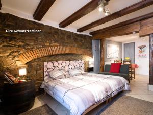 1 dormitorio con paredes de piedra, 1 cama grande y sillas en Gîtes de la Maison Vigneronne, au Coeur de Ribeauvillé, en Ribeauvillé