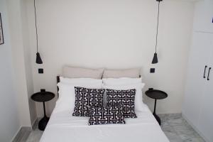 1 dormitorio con cama blanca y almohadas blancas y negras en Ermis Mini Suite # 01, en Chalkida