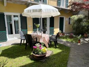 een tafel met een parasol, wat stoelen en bloemen bij Arancio in Verbania