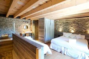 sypialnia z dużym łóżkiem i kamienną ścianą w obiekcie Duplex Cal Josepo w mieście Ger