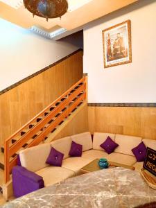 Hotel Aladarissa Ait Baha في Aït Taksimt: غرفة معيشة مع أريكة مع وسائد أرجوانية