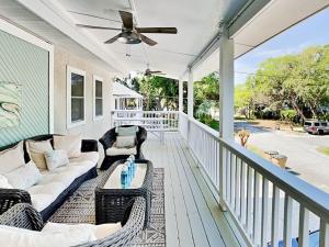 a porch with a couch and chairs and a ceiling fan at Boho Beach House in Tybee Island