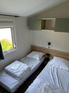 2 letti in una piccola camera con finestra di Camping La sablière a Saint-Jans-Cappel