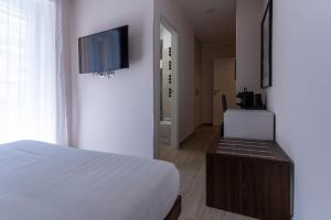 1 dormitorio con 1 cama y TV en la pared en MAMA GUEST HOUSE, en Ciampino
