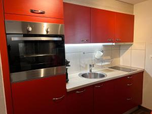 una cocina con armarios rojos y fregadero en Au Bon Vieux Temps, en Zinal