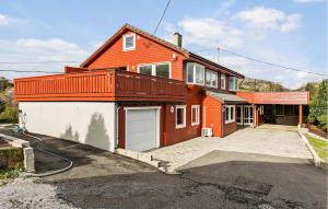 a orange house with a garage in front of it at Beautiful Apartment In Hellvik With House Sea View in Hellvik