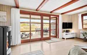 a living room with a sliding glass door with a table at 3 Bedroom Pet Friendly Home In Hvide Sande in Hvide Sande
