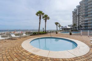 a swimming pool with palm trees and a beach at Windward Pointe 706 in Orange Beach
