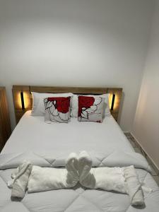 Una cama con sábanas blancas y rosas rojas. en Lacazavanoo en Baillif